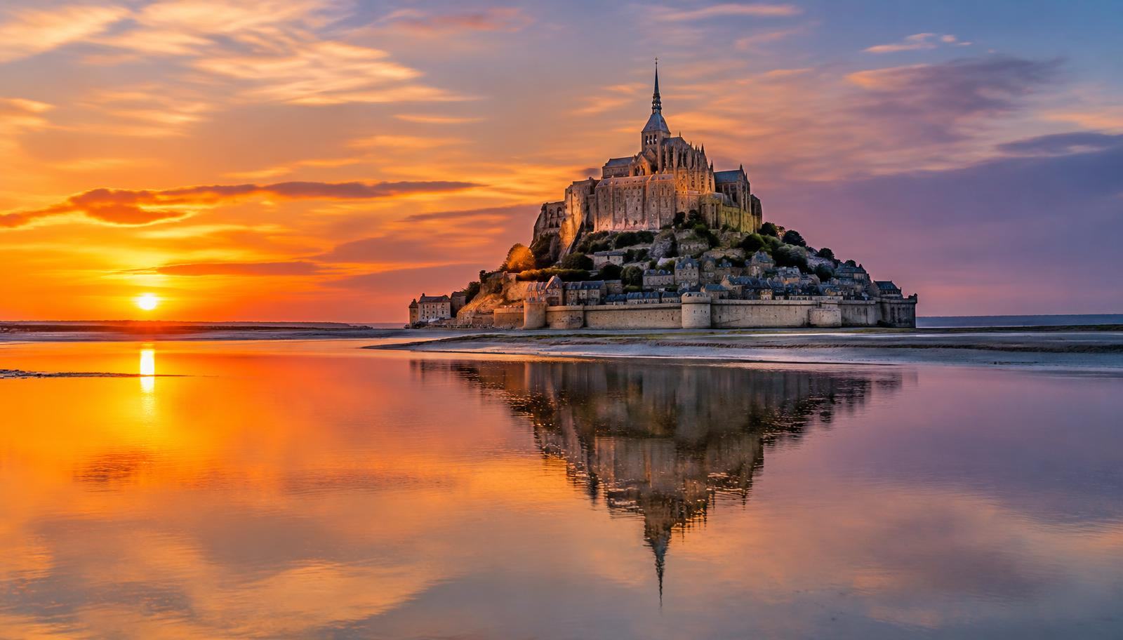 Mont-Saint-Michel et son abbaye au coucher du soleil, reflétés dans la baie